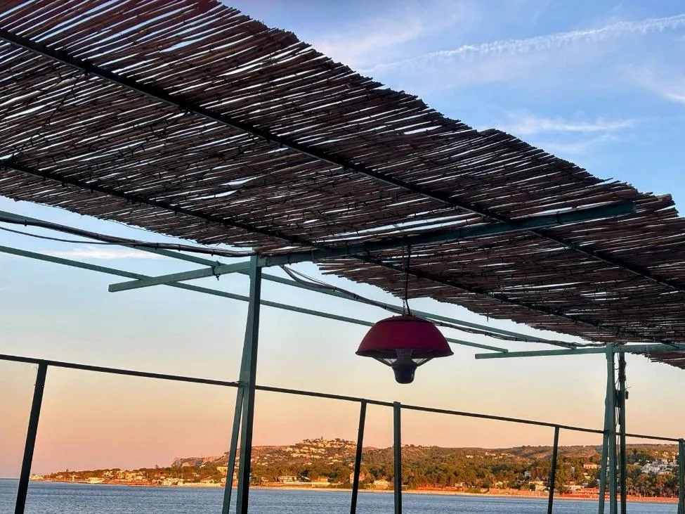 Terras met rieten dak en uitzicht op de kust bij zonsondergang