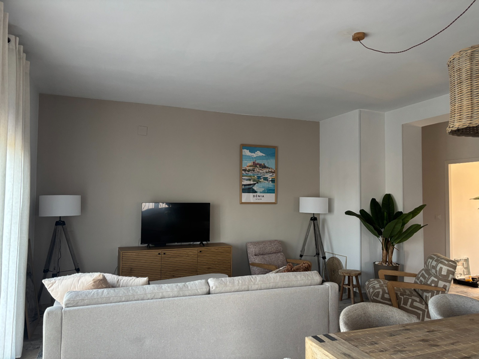 Lichte woonkamer met loungebank, smart TV en eethoek in Appartement Boven
